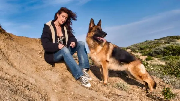 German Shepherd Dog with a girl sitting in mountain