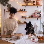 Woman Putting Christmas Cookies on a Tray and Her Dog Watching Her