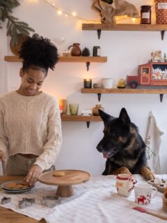 Woman Putting Christmas Cookies on a Tray and Her Dog Watching Her